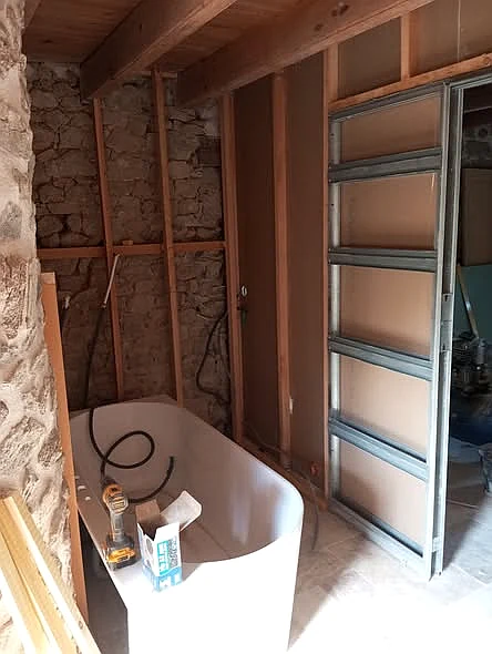 Salle de bain en cours de rénovation avec cloison et baignoire